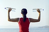 Junge Frau am Strand mit zwei Wasserflaschen in der Hand