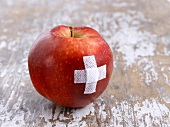 Ein roter Apfel mit Pflaster als Kreuz