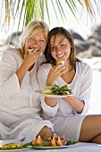 Mother and daughter eating pineapple on the beach