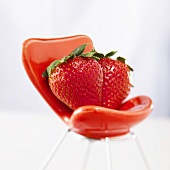 Two strawberries on a tiny red chair