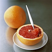 Half a grapefruit with spoon and whole grapefruit