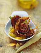 Roasted figs wrapped in ham on orange segments