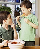 Two boys licking chocolate cake mixture