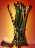 Bundle of green asparagus against orangey-red background