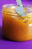 A jar of apricot jam with knife