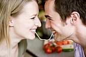 Young couple eating the same strand of spaghetti