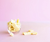 Broken white chocolate in and beside a glass dish
