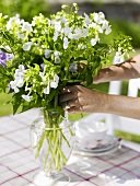 Kaffeetisch im Garten mit einem Blumenstrauss dekorieren