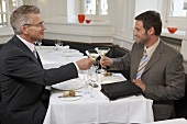 Two men clinking glasses of Martini in a restaurant