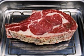 A beef cutlet on a rack in a roasting tin