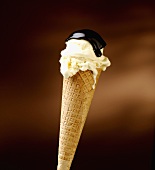 A vanilla ice cream cone with chocolate sauce
