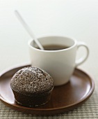 A chocolate muffin with a cup of coffee on a plate