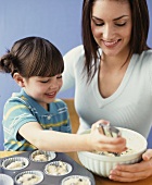 Mother and daughter baking muffins together