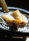 Taking deep-fried spring rolls out of the frying oil