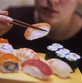 Frau hält Nigiri-Sushi auf Essstäbchen