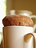 A Sugared Donut on Top of a Mug