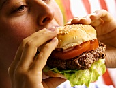 A Woman Biting into a Hamburger
