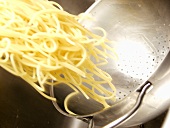 Gekochte Spaghetti aus dem Sieb nehmen