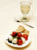 Mozzarella mit Tomaten und Basilikum; Glas Weißwein