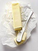 Stück Butter auf Einwickelpapier mit Buttermesser