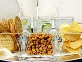 Crackers, Erdnüsse und Chips; Gin Tonic