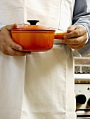 Holding an Orange Pot with Lid