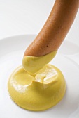 Dipping a sausage in mustard