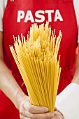 Spaghetti, person with 'pasta' apron in background
