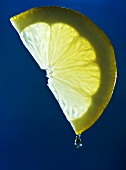 Zitronensaft tropft von einer Zitronenspalte