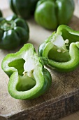 Green peppers, whole and halved, on a chopping board