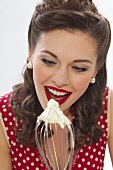 A retro-style girl licking cream off a whisk