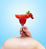 Schwangere Frau hält alkoholfreien Drink auf ihrem Bauch