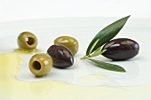 Oliven mit Blättern und Olivenöl auf Teller