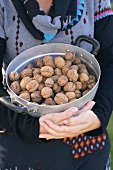 A woman holding a pot of walnuts