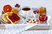 Breakfast in bed with tea, jam, yogurt, fruit and tomatoes and mozzarella