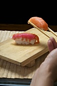 Hand hält Sushi mit Essstäbchen