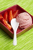 Strawberry ice cream with fresh strawberries in a bowl with a spoon