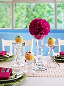 A festively laid table with flower balls and cupcakes