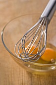 Whisk and egg yolk in a glass mixing bowl