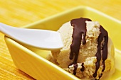 A scoop of banana ice cream with chocolate sauce