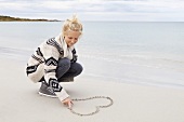 Teenager drawing a heart in the sand at the beach