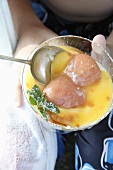 Hands holding a bowl of Crimpolene Pudding (vanilla pudding with tinned fruit)