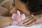A young woman lying on a massage table with orchid flowers