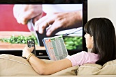 A woman reading a TV listings magazine