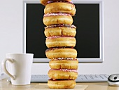 A stack of doughnuts in front of a computer