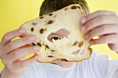 A boy looking through a slice of raisin bread