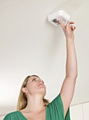 A woman testing a smoke alarm