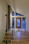 Flurbereich eines Hauses mit Parkett, Tierfellvorleger & Treppenabgang mit Glasgeländer