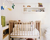 Baby-Schlafzimmer mit Teddybären im Kinderbett und einem lustigen Tiermobile