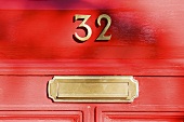 A red front door with a house number and a letter box